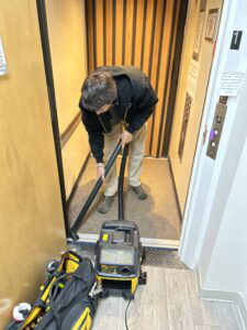 Image of Elevator Works crew member vacuuming after residential elevator installation.